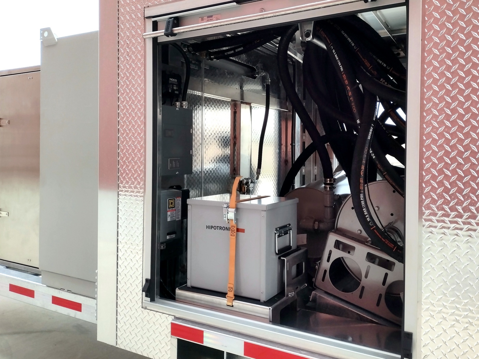 Left side view of a Sauber Model 1594 Oil Filtration Trailer's rear aluminum compartment side door. The door is open showing storage for a Hipotronic measuring device and electronic controls.