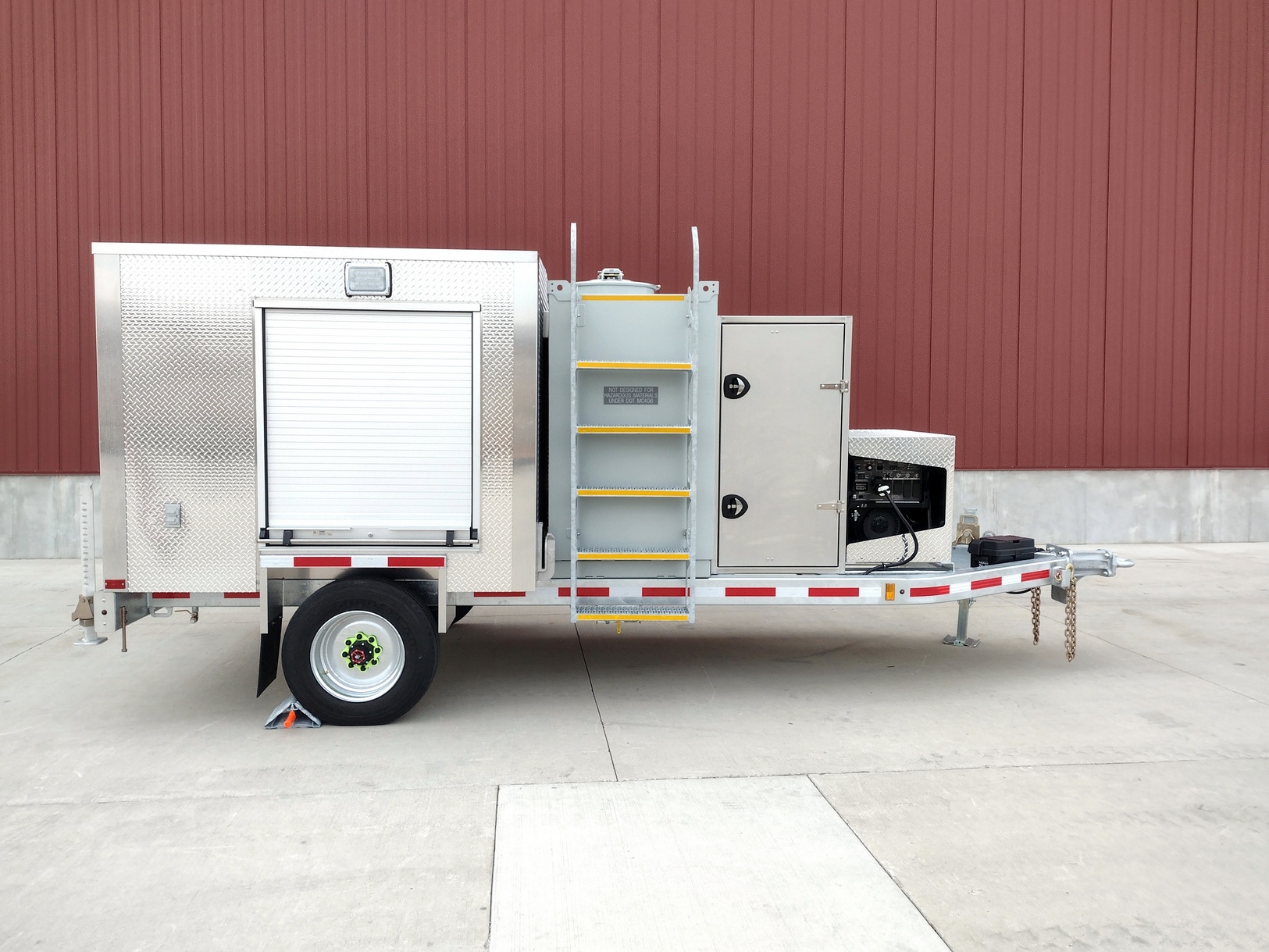 Right side view of a Sauber Model 1594 Oil Filtration Trailer with galvanized finish on concrete with red building in the background