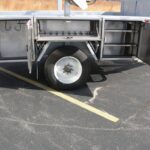 Close right side view of a Sauber Model 1560 Reel Four-In-One Reel Cargo Trailer stainless-steel toolbox package with side opening doors. It is shown on pavement in front of a brown prairie grass field.