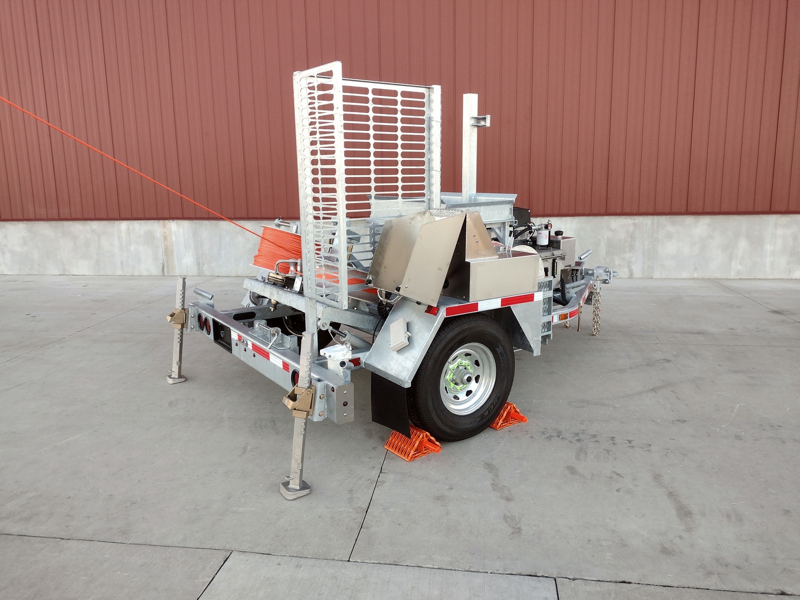 Right side rear view of the Sauber Model 1570-B Puller with orange pulling rope installed. The trailer has galvanized finish and is shown on concrete in front of a red metal building.