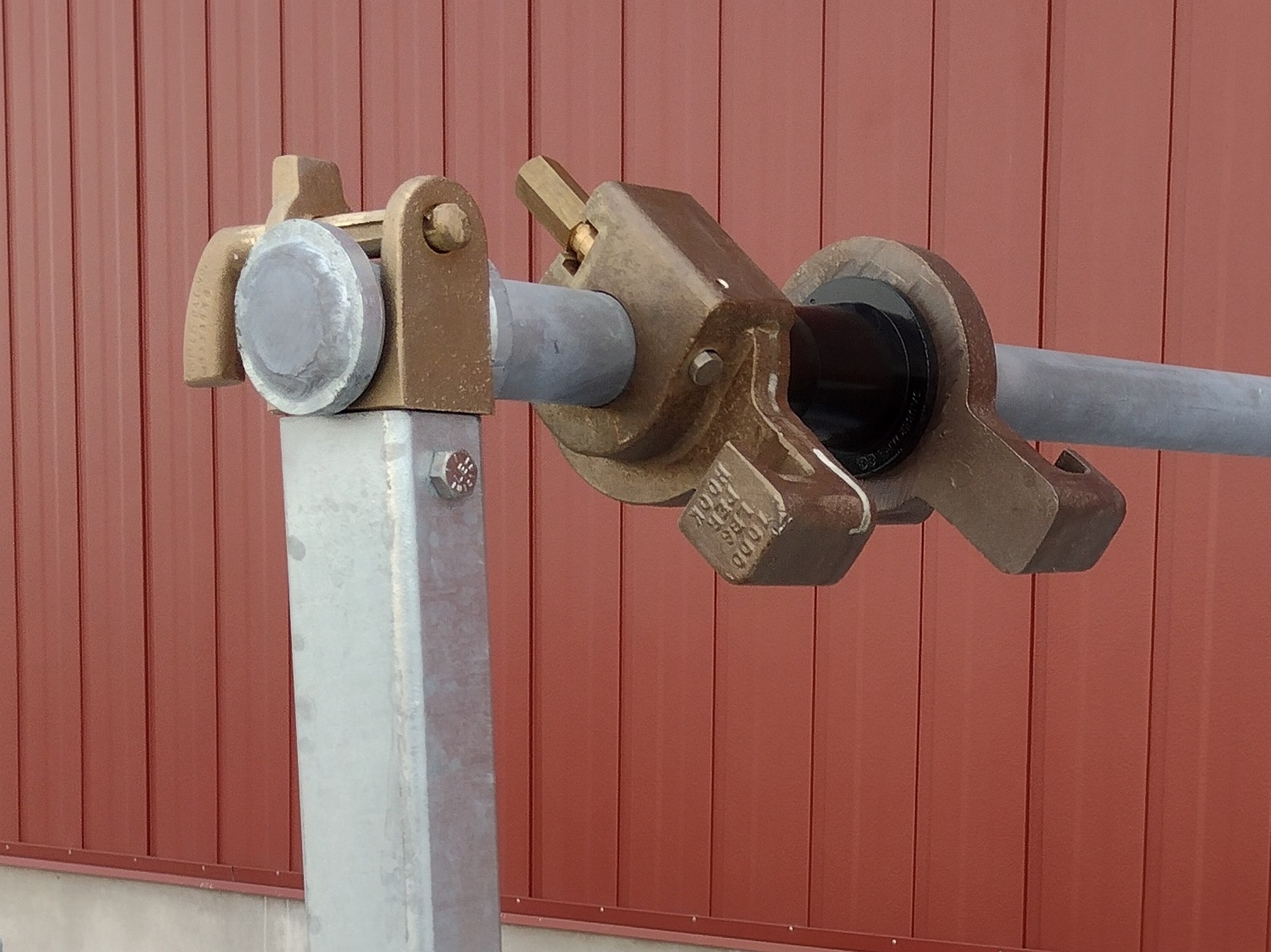 Image showing a Sauber Mfg. Co. Reel Bar, Saddle and Positioning Collar with tapered sleeve in front of a red metal building.