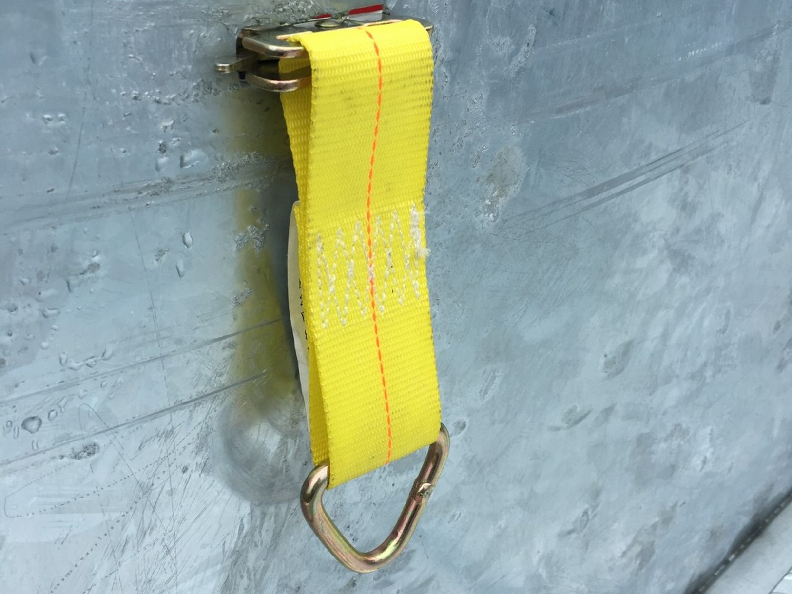 Close view of a galvanized Sauber Mfg. Co. LogiPerf Trailer Side showing a yellow logistics strap component installed.