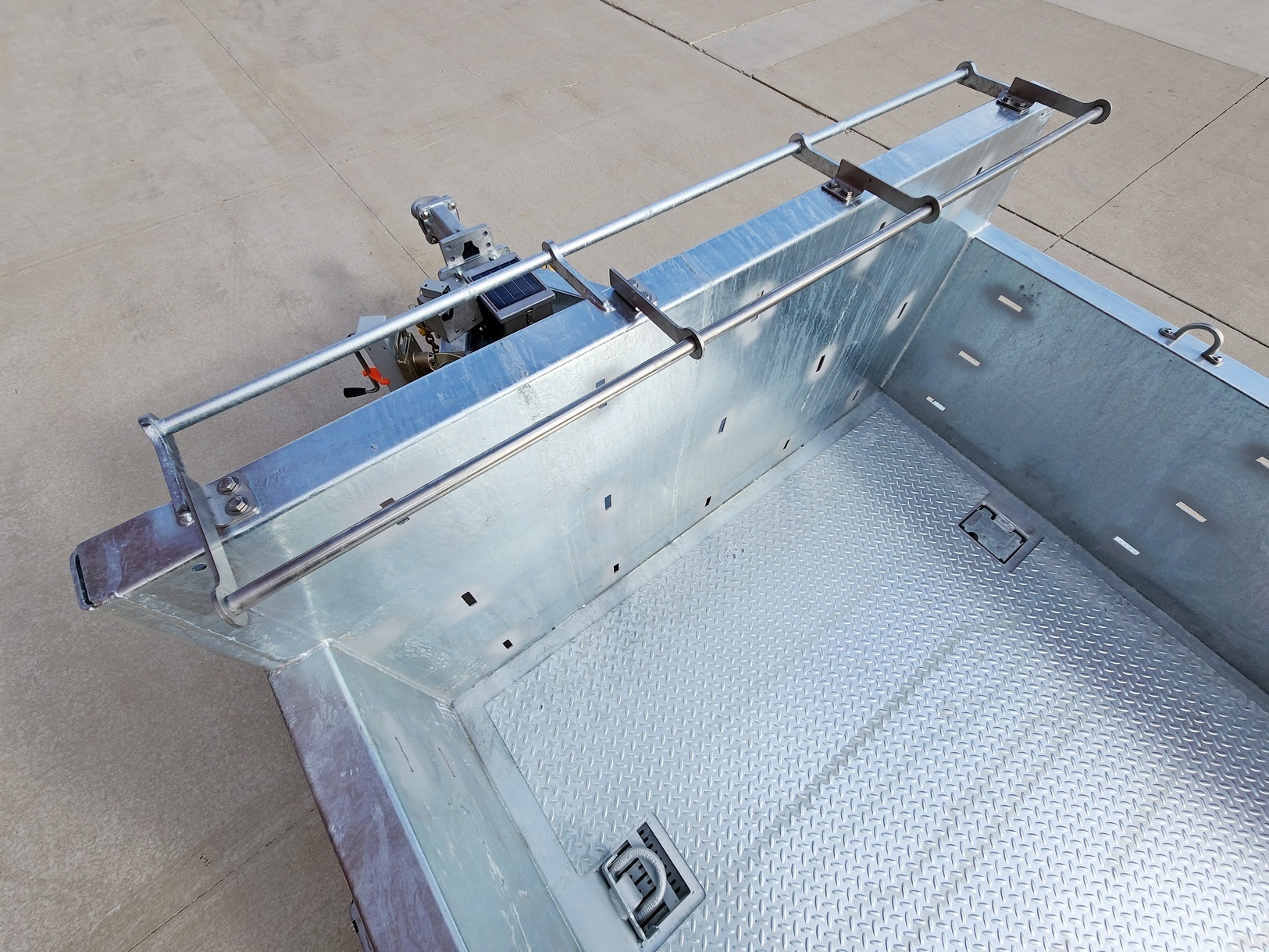 Overhead close view of a Sauber Model 1560 Cargo Trailer's material rail and cargo area including recessed d-rings and SmartPerf cargo walls compatible with logistics track components. The trailer is on concrete.